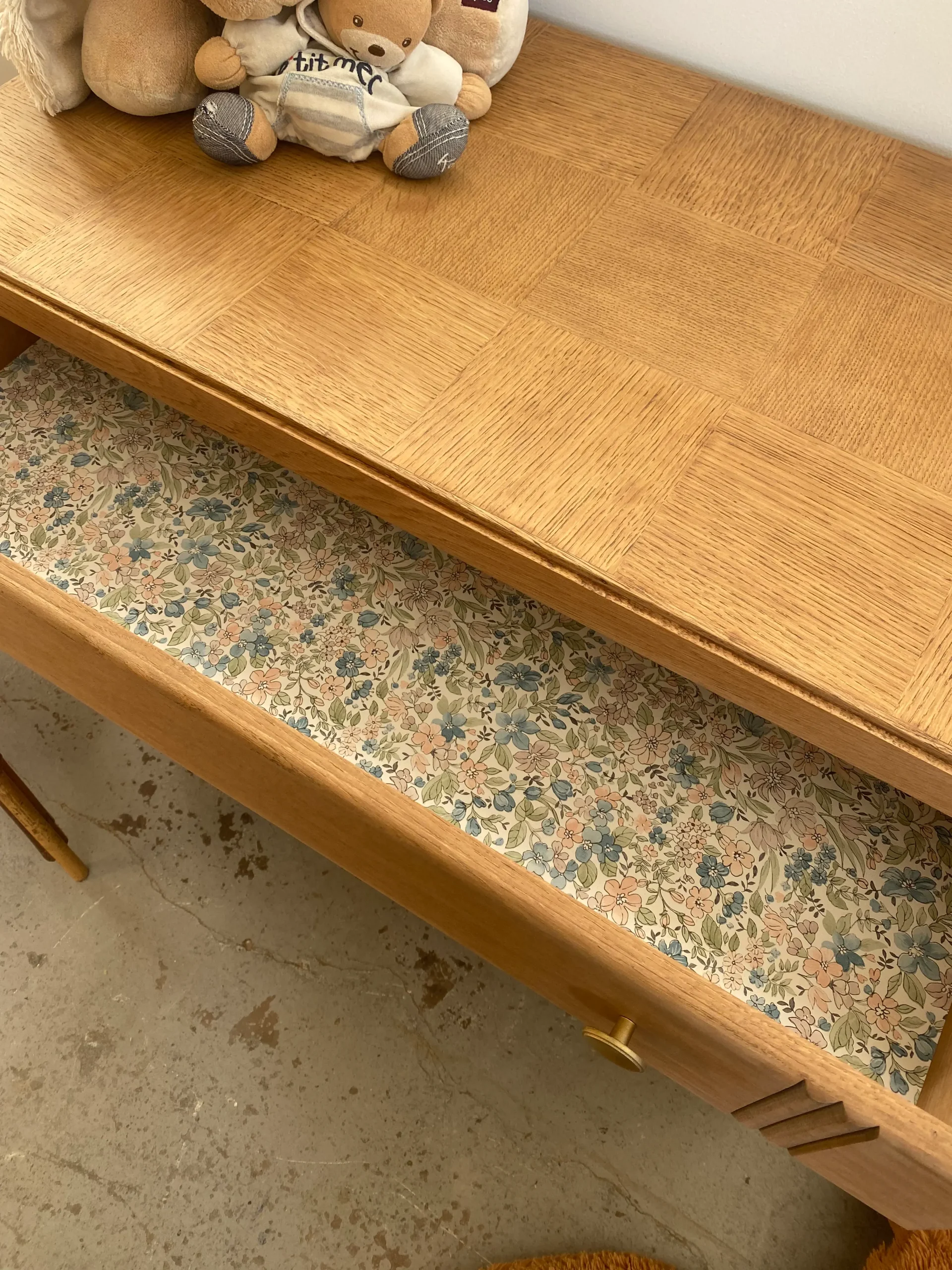 détail d'un tiroir de commode avec un papier peint fleuri dans le fond. Meuble dispo à l'atelier Cornet Citron à côté de Gelos